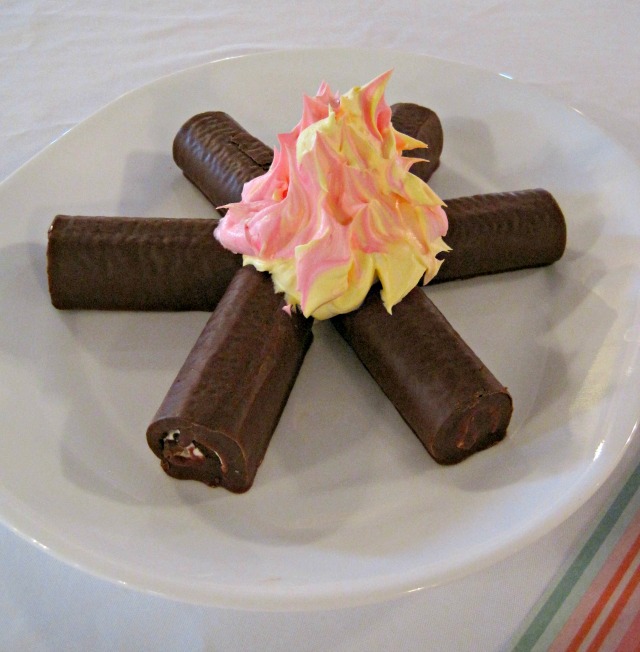 A "campfire" dessert of pastry rolls and colored whipped cream made every table cozy! | Retro Camper RV themed party dessert Edible campfire ho-hos and whipped cream fire cake dessert